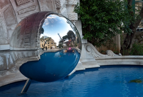 Immagine con acqua, sfera, fontana, riflesso, alberi, albero, riflessi, blu, azzurro, palla, specchio, case