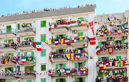 Immagine con bandiere, finestre, balconi, colori, persone, palazzo, palazzi