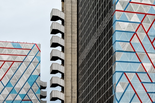 Immagine con grattacieli, scale, rosso, linee, azzurro, geometrie, triangoli, colori, blu, palazzi, cielo, finestre, balconi, terrazze, bianco, grigio, architettura, righe, grattacielo